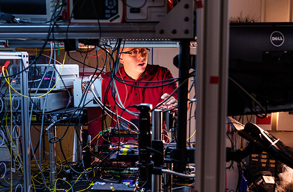 Nils Otterstrom works to align an integrated photonics chip as part of work to combine integrated photonics and frequency-encoded quantum information processing. 