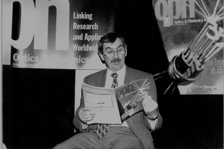 Duncan Moore reading a copy of Optics and Photonics News
