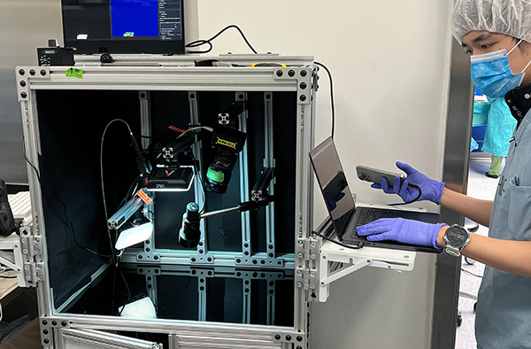 a male scientist looking at a computer attached to a rectangular device