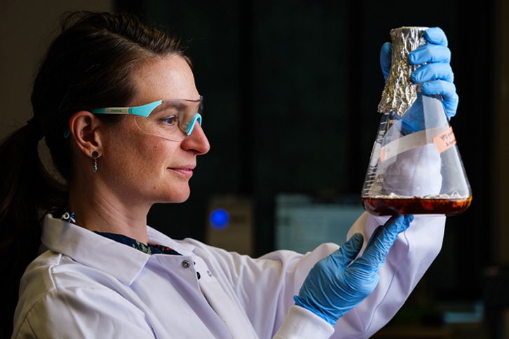 Tess Eidem holds up a jar of fungus used to generate allergens for research. 