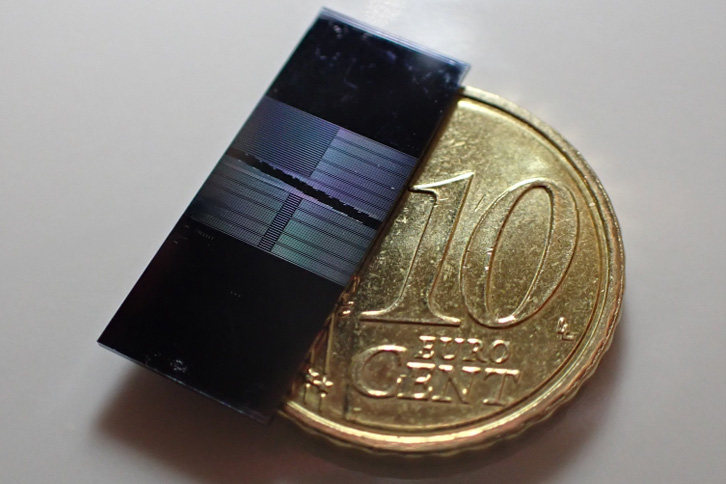 A photonic microchip next to a 10-euro-cent coin